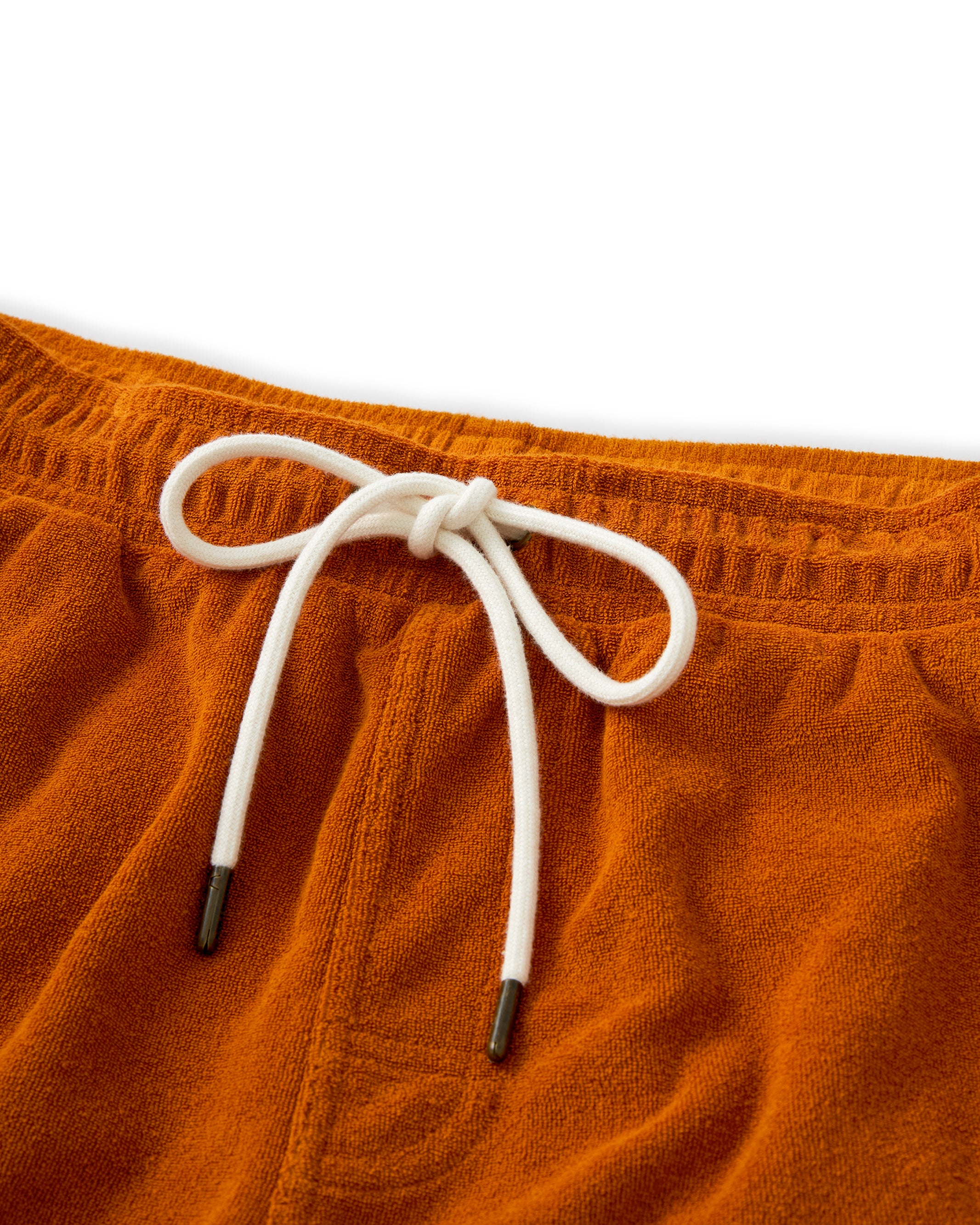 Close-up of The Tropez Shorts by Dandy Del Mar in Burnt Sienna, featuring a white drawstring tied in a neat bow, capturing the playful spirit of the Côte d'Azur.