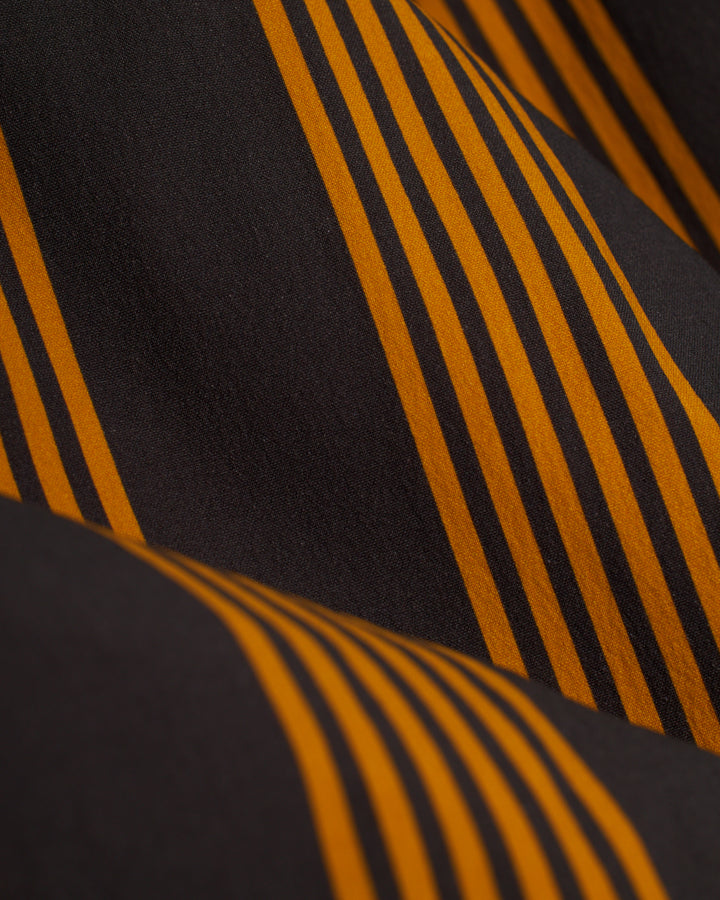 A close up of The Ventura Volley Short - Albatross by Dandy Del Mar, an orange and black striped fabric.