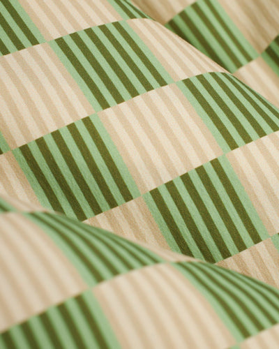 Close-up of the soft, checkered beige and green fabric of The Ventura Volley Shorts - Arbequina by Dandy Del Mar, showcasing the wavy texture and comfortable elastic waist ideal for swim trunks.