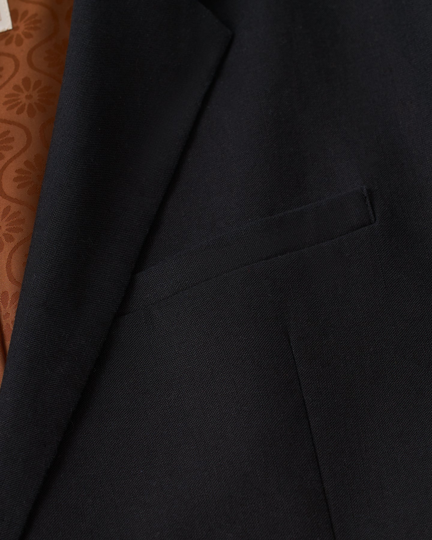 A close up of the Dandy Del Mar Brisa Linen Blazer - Onyx with a brown pocket.