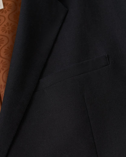 A close up of the Dandy Del Mar Brisa Linen Blazer - Onyx with a brown pocket.