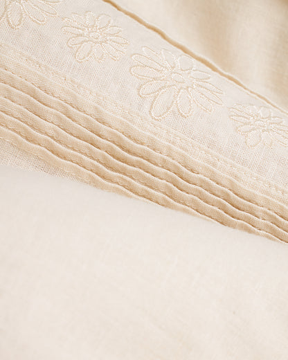 A close up of a bed with The Brisa Linen Shirt - Vintage Ivory linens from Dandy Del Mar.