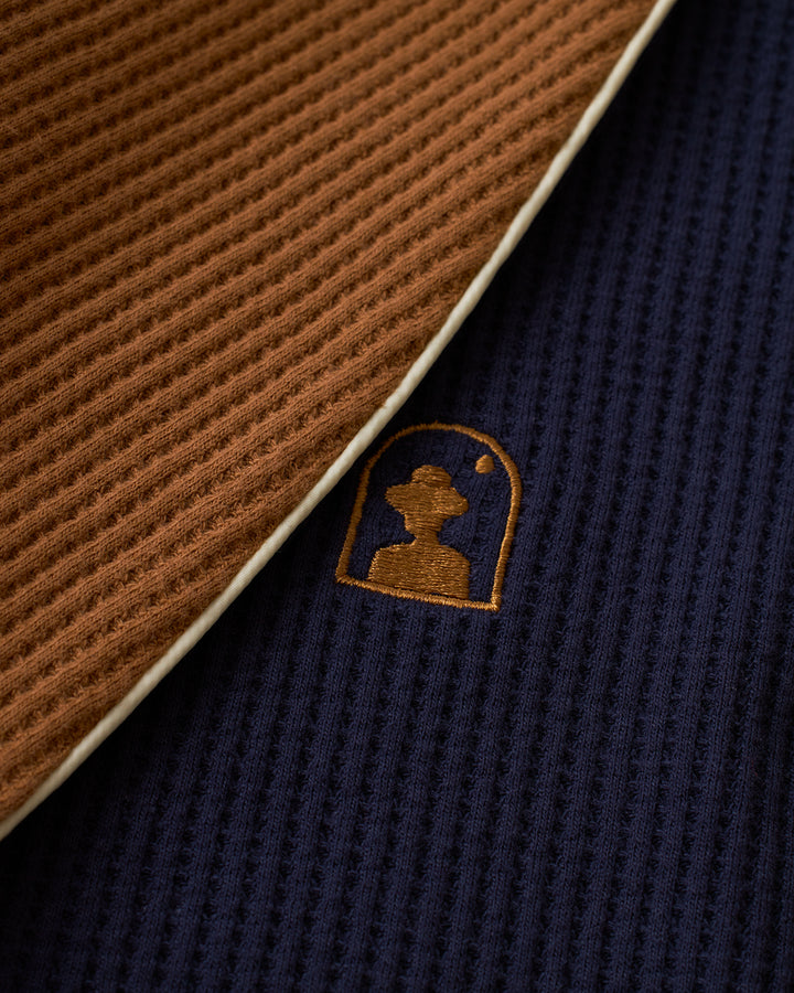 A close up of the Dandy Del Mar Cannes Robe - Luxe Navy sweater with a logo on it.