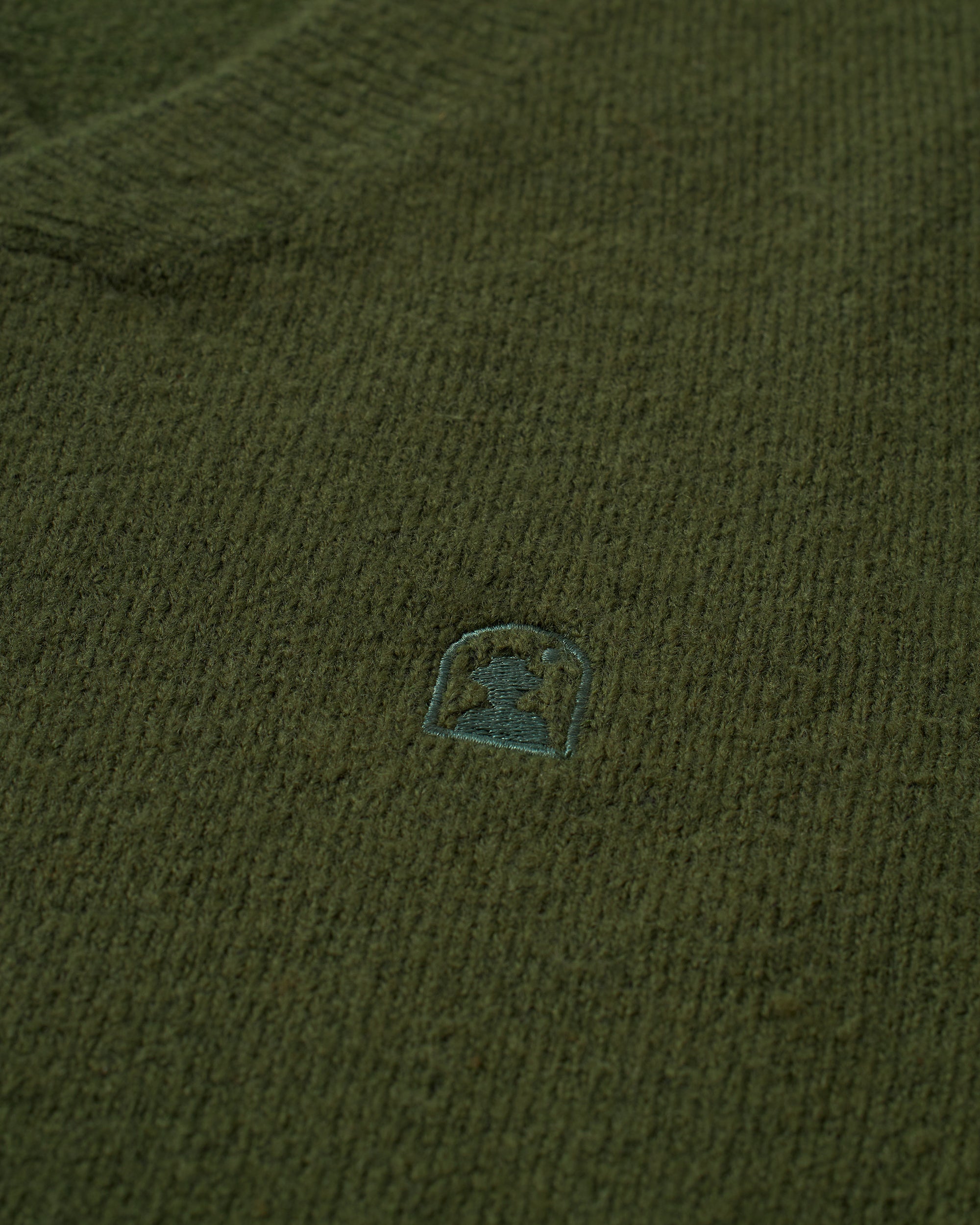 A close up of The Lima Sweater - Selva by Dandy Del Mar with a small logo on it.