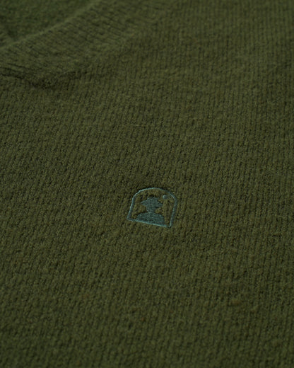 A close up of The Lima Sweater - Selva by Dandy Del Mar with a small logo on it.