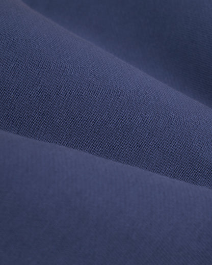 A close-up image of blue fabric with a smooth texture and a tightly woven pattern, reminiscent of the classic French Terry used in the stylish "The Marseille French Terry Pullover - Moontide" by Dandy Del Mar.