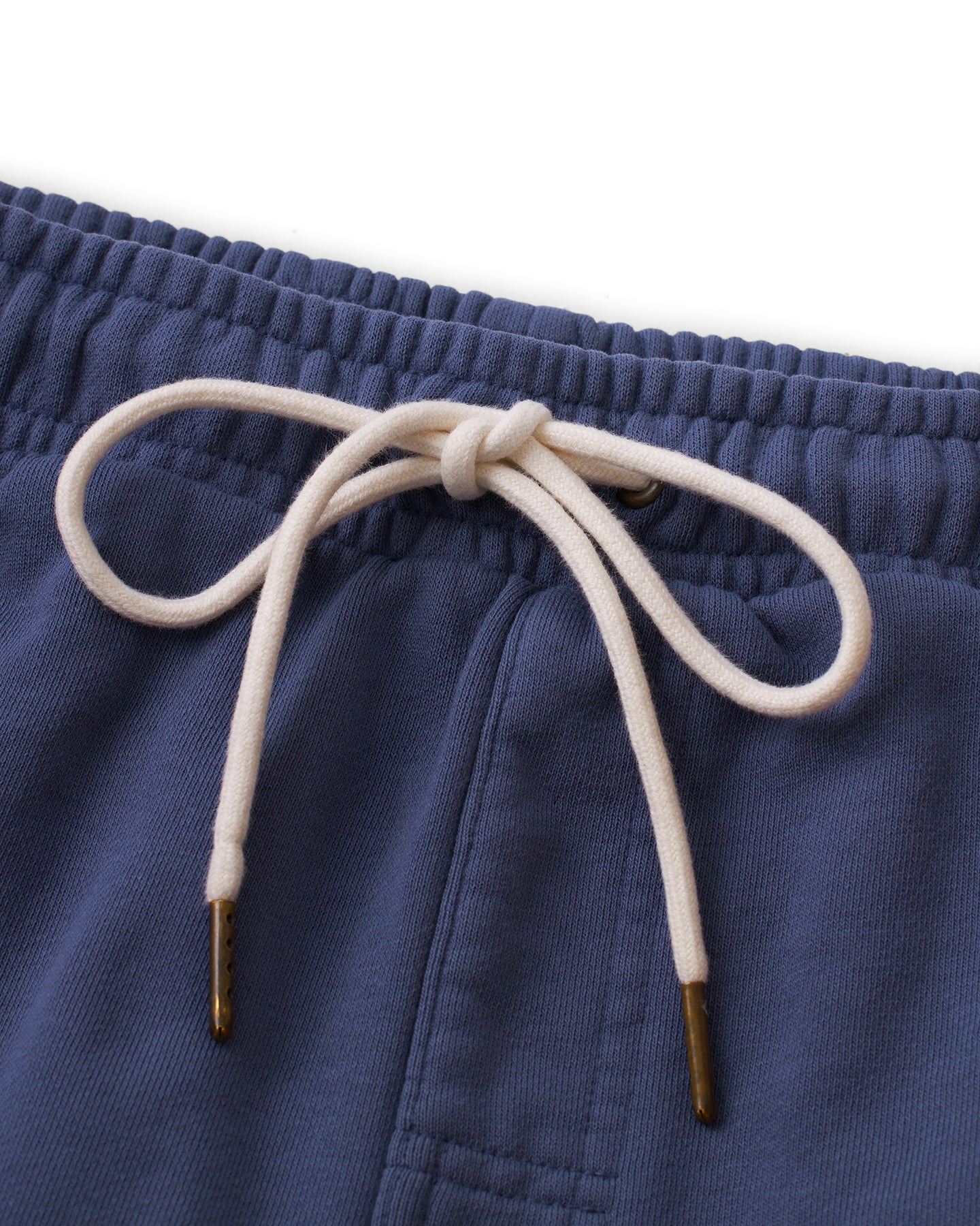 Close-up image of The Marseille French Terry Short - Moontide by Dandy Del Mar, featuring a blue fabric with a white drawstring tied in a bow. The soft material and elasticized waistband are clearly visible.