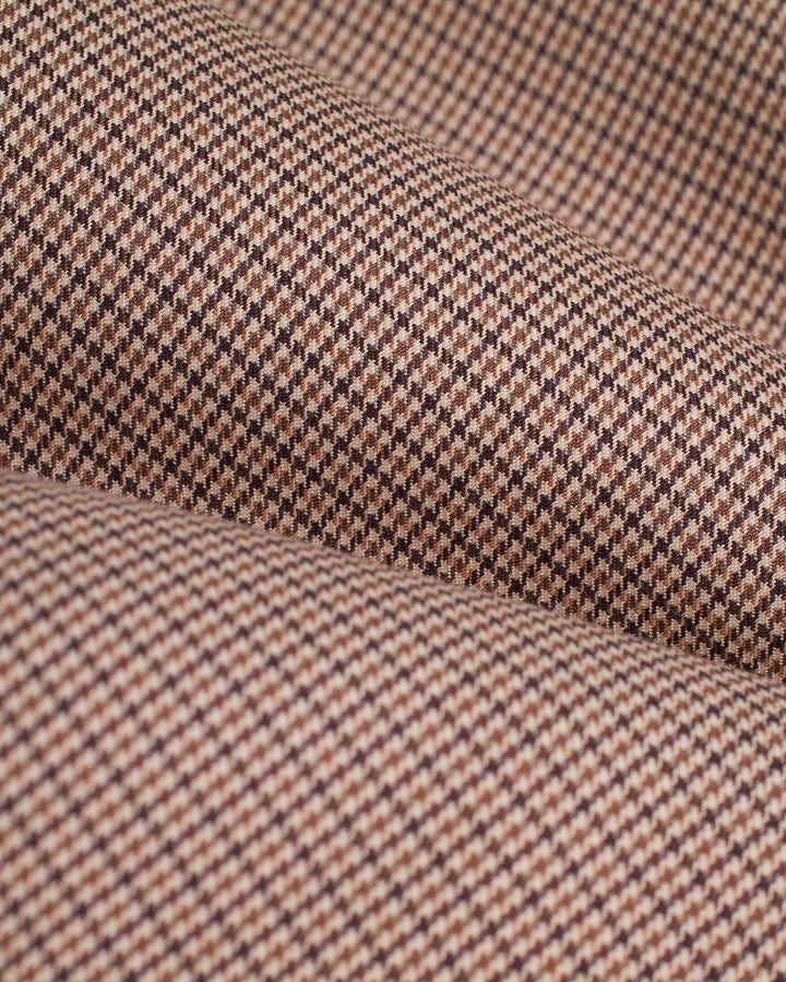 A close up of The Tresco Trouser - Carajillo in Dandy Del Mar brand, a brown and black checkered fabric.