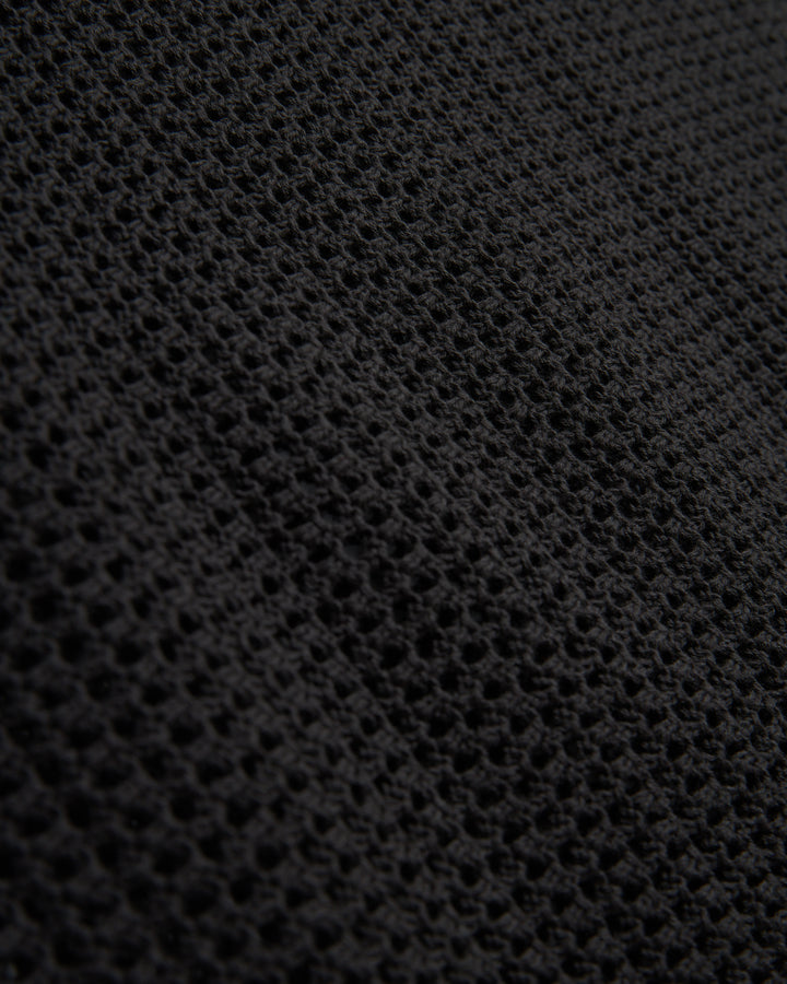Close-up of a black textured Dominica Crochet Tank by Dandy Del Mar with a honeycomb-like pattern.