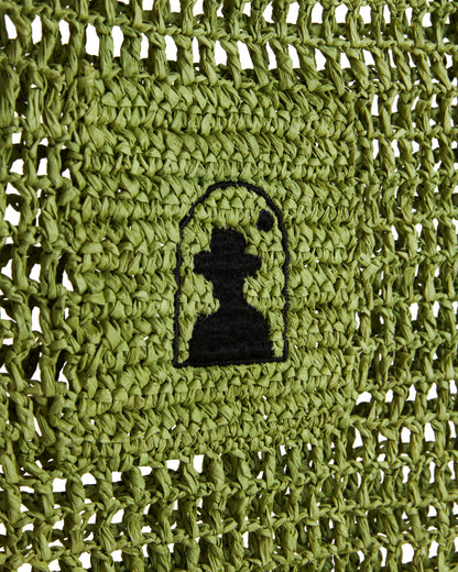 Green crochet design featuring a black silhouette of a person wearing a hat, enclosed in an arch, crafted with raffia-effect yarn, inspired by The Amabile Raffia Bag - Verde from Dandy Del Mar.