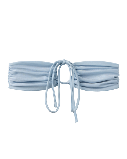 The Biarritz Top - Comet by Dandy Del Mar features a light blue tie-front bandeau design with ruched fabric and cinch detail for a versatile fit, displayed on a plain background.