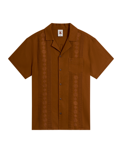 The Brisa Linen Shirt - Sedona by Dandy Del Mar is a short-sleeve brown linen shirt featuring coconut shell buttons, embroidered vertical patterns, and a single chest pocket, displayed on a plain background.