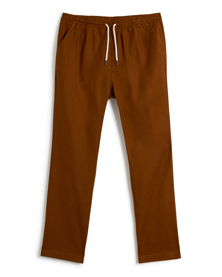 A pair of The Brisa Linen Pant - Sedona by Dandy Del Mar in brown, featuring an elastic waist and side pockets, is showcased against a white background. Perfect vacation wear.