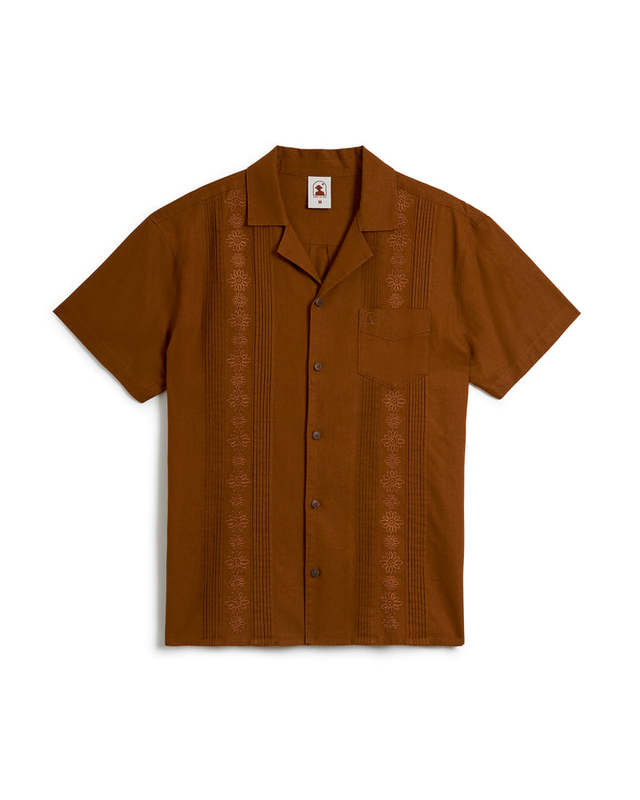 The Brisa Linen Shirt - Sedona by Dandy Del Mar is a brown short-sleeve button-up featuring gardenia floral embroidery along the vertical patterns on both sides of the button line and a single chest pocket.