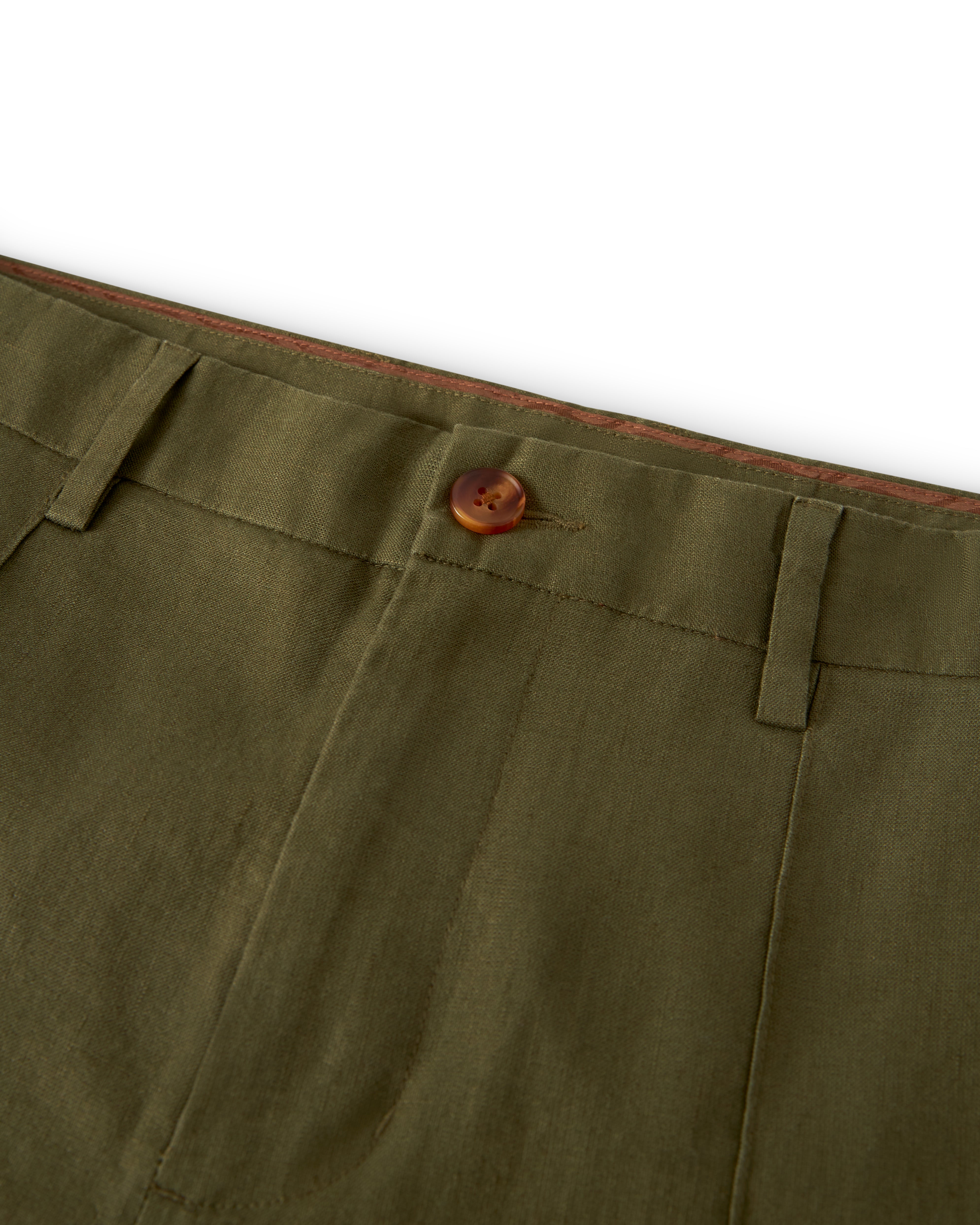 Close-up of the waistband of a pair of The Brisa Linen Trouser - Berdea from Dandy Del Mar, showcasing a brown button and belt loops.