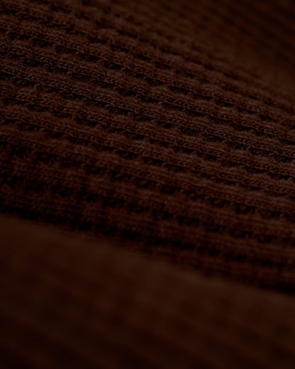 A close-up view of the brown 100% cotton fabric with a waffle weave pattern, reminiscent of the exquisite texture found in Dandy Del Mar's The Cannes Waffle Knit Robe - Carajillo.