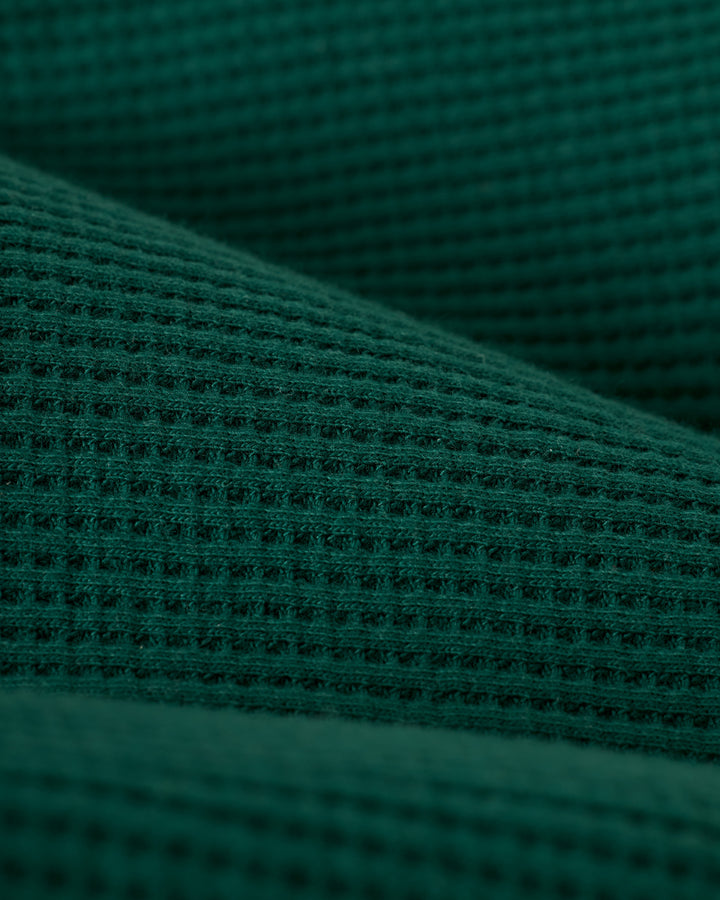 Close-up of The Cannes Waffle Knit Shirt - Albero by Dandy Del Mar, featuring a textured green fabric with a grid-like pattern.