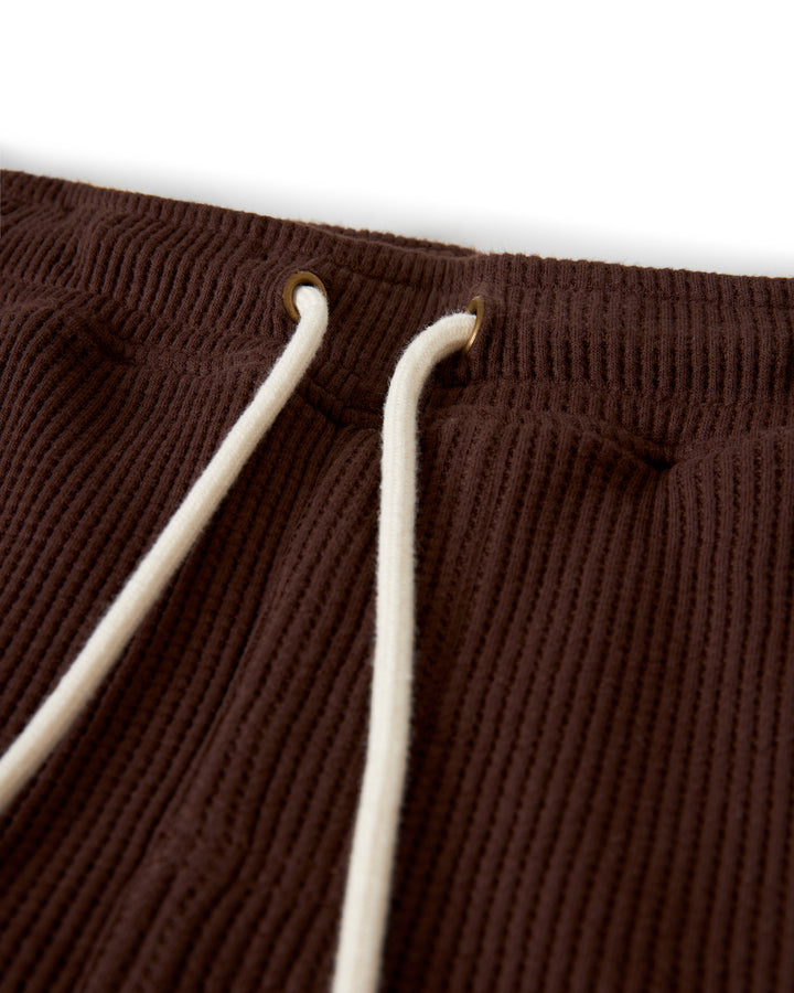 Close-up of The Cannes Waffle Knit Shorts - Carajillo by Dandy Del Mar, featuring a white drawstring threaded through brass eyelets at the elastic waistband.