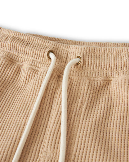 Close-up of the waistband of The Cannes Waffle Knit Shorts - Truffle by Dandy Del Mar, featuring white drawstrings threaded through metal eyelets, made from 100% cotton.