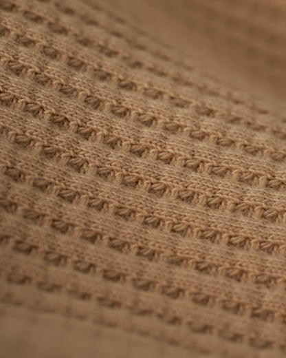 Close-up of the beige waffle knit fabric with a textured pattern of horizontal and vertical stitches, showcasing the embroidered Dandy Del Mar logo on The Cannes Long Sleeve Shirt - Truffle.