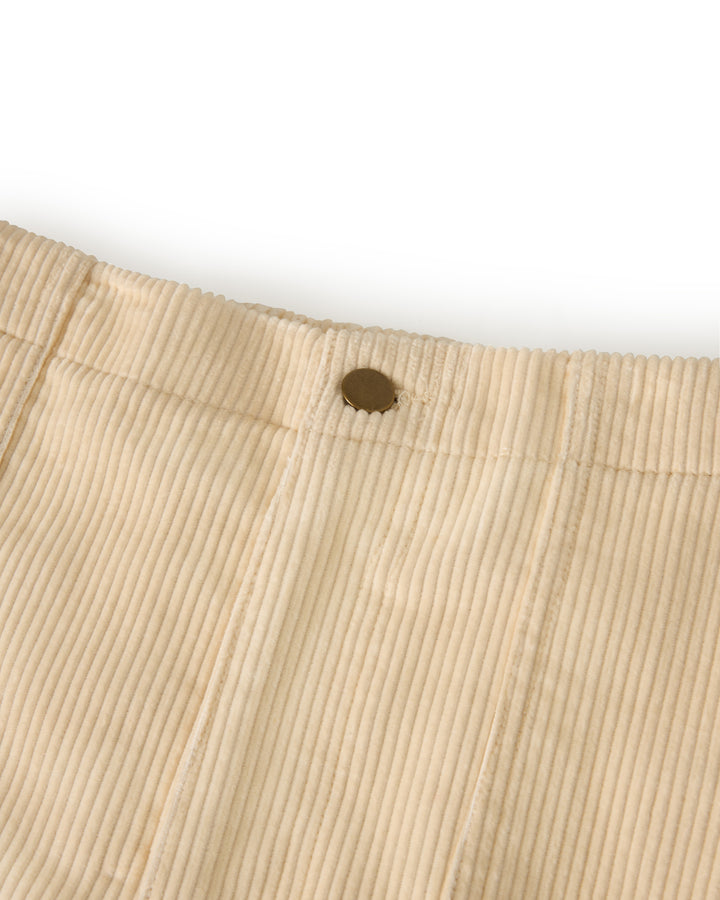 Close-up of The Corsica Corduroy Short - Scallop by Dandy Del Mar, showcasing beige corduroy fabric with a visible button at the waistband.