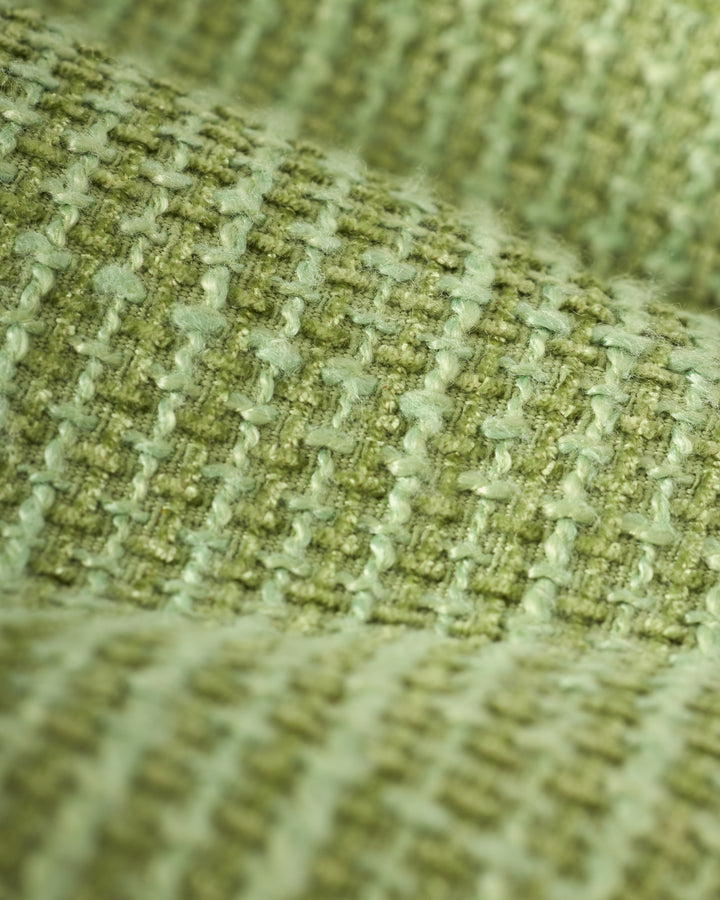 Close-up of The Trinidad Tweed Strapless Dress - Oliva by Dandy Del Mar, featuring textured green fabric with a woven pattern reminiscent of classic tweed, showcasing raised and indented areas.