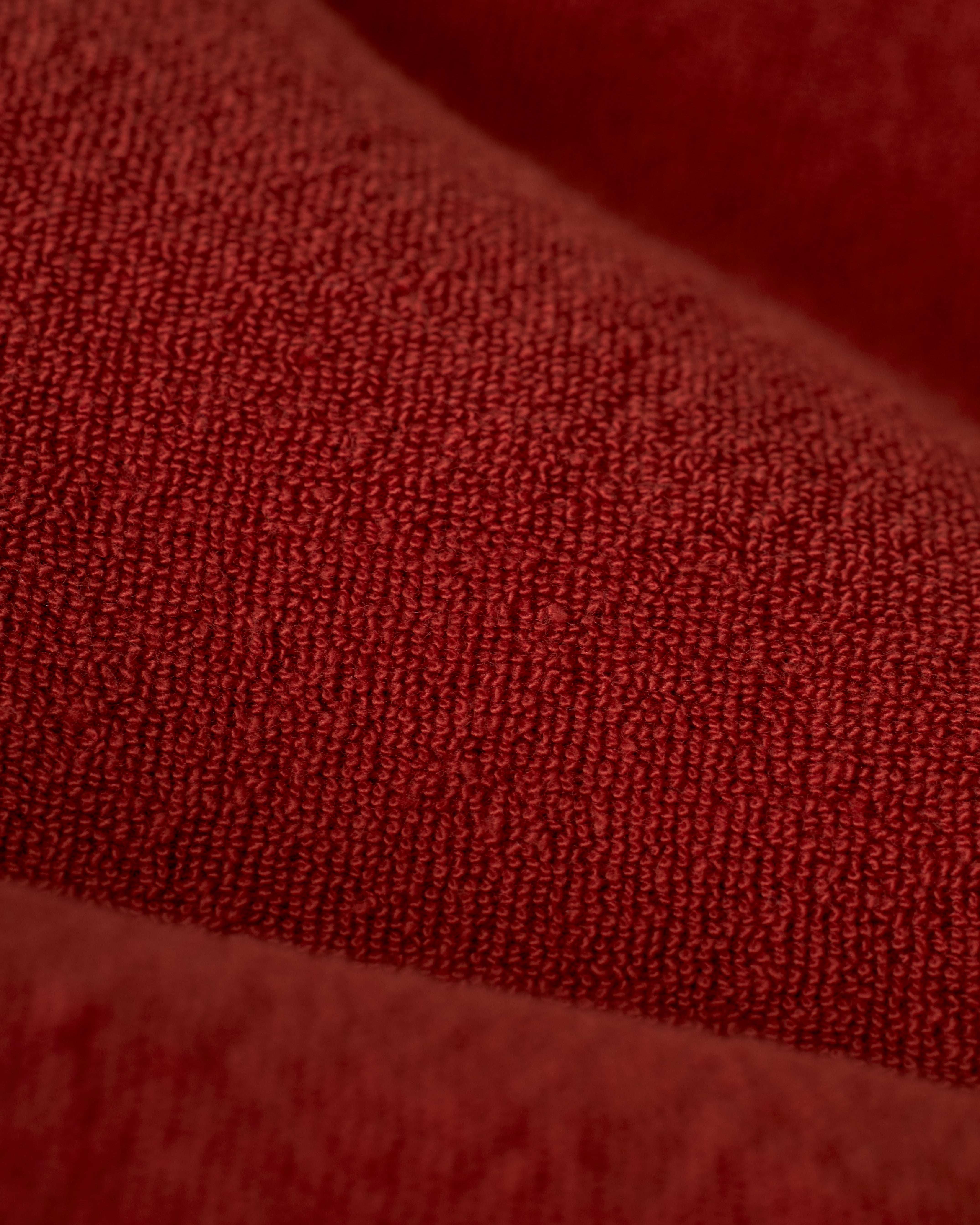 Close-up of The Gaucho Short - Rouge by Dandy Del Mar, highlighting the fibrous surface and subtle shadows of its red terry cloth fabric.