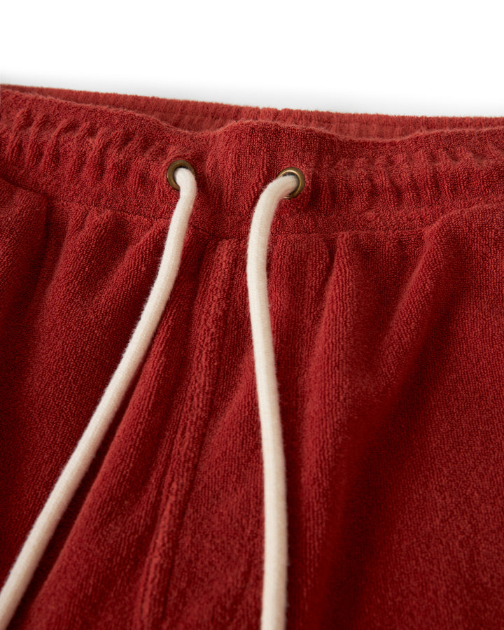 Close-up of the Dandy Del Mar Gaucho Terry Cloth Short - Rouge showing the elastic waistband, metal eyelets, and white drawstrings. The ultra-soft terry cloth fabric has a soft, textured appearance.