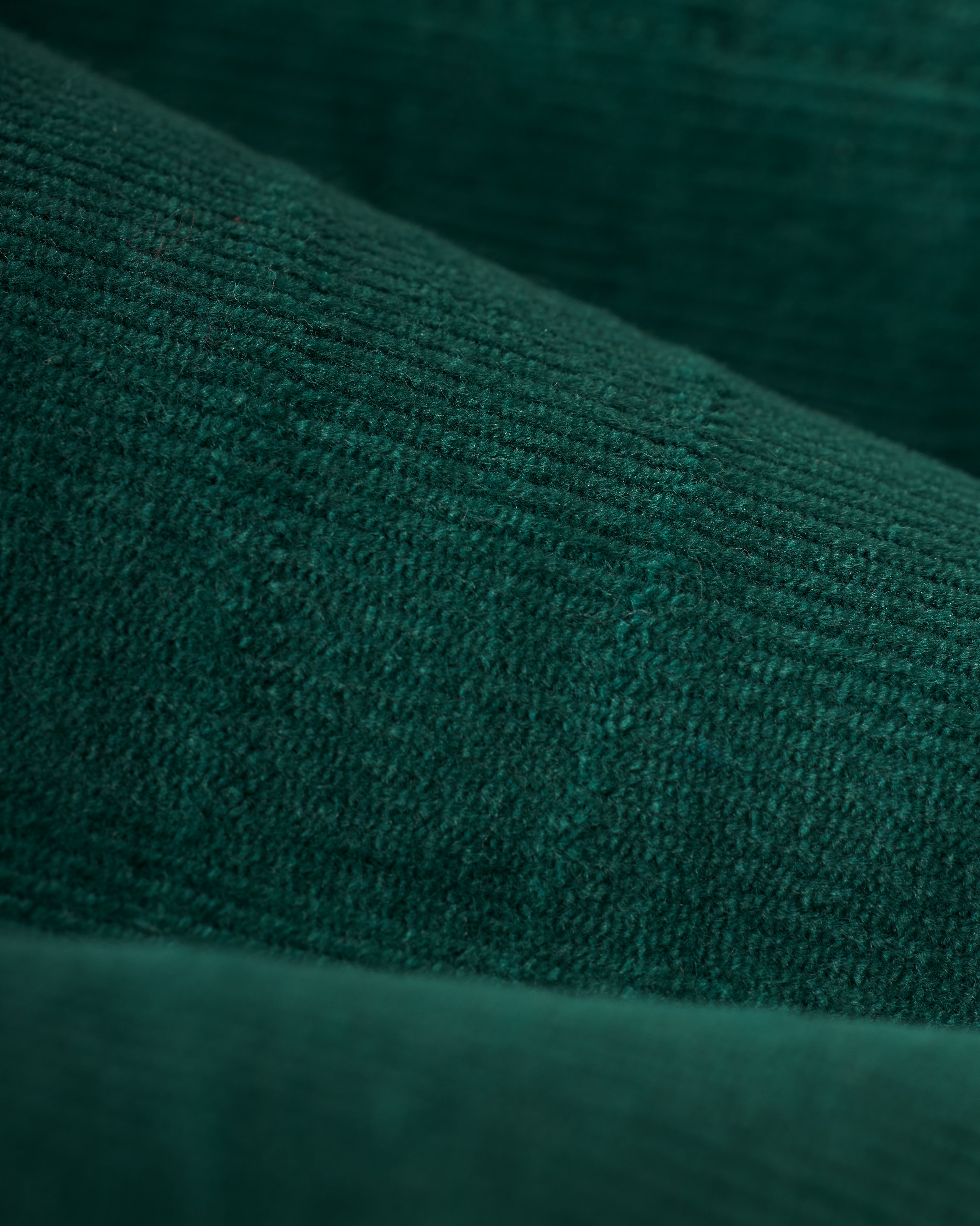 Close-up of dark green textured fabric with visible lines and subtle grid patterns, reminiscent of the Albero version of The Kitts Corduroy Dress by Dandy Del Mar.