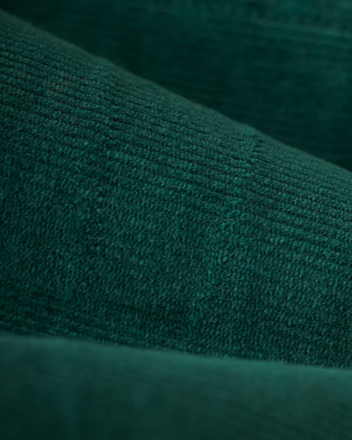 Close-up of dark green textured fabric with visible lines and subtle grid patterns, reminiscent of the Albero version of The Kitts Corduroy Dress by Dandy Del Mar.