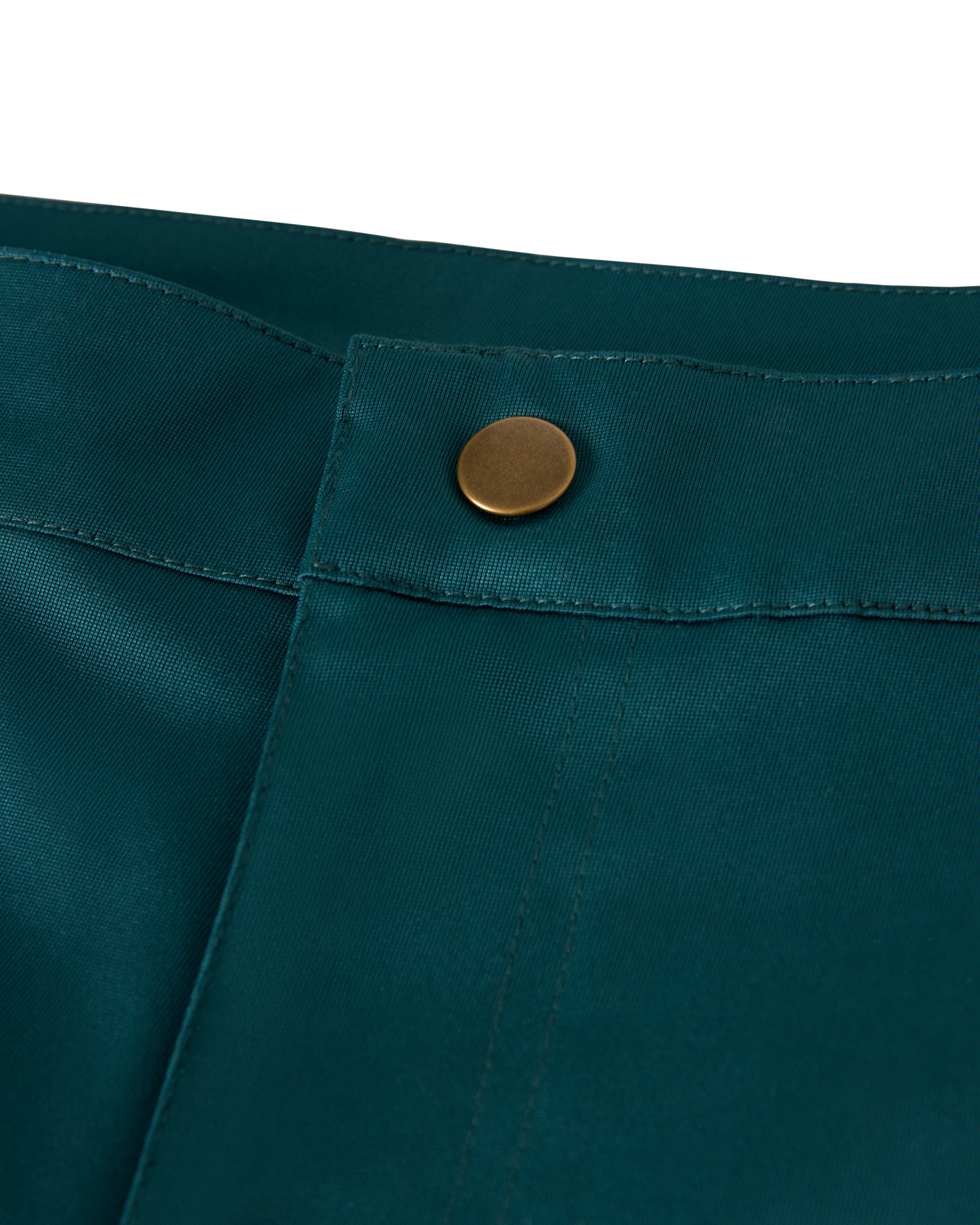 A close-up of the Tempest Blue Mallorca Swim-Walk Short by Dandy Del Mar shows its teal fabric, adjustable brass side fastener, and distinct brass-colored waistband button, combining nylon construction for durability and style.