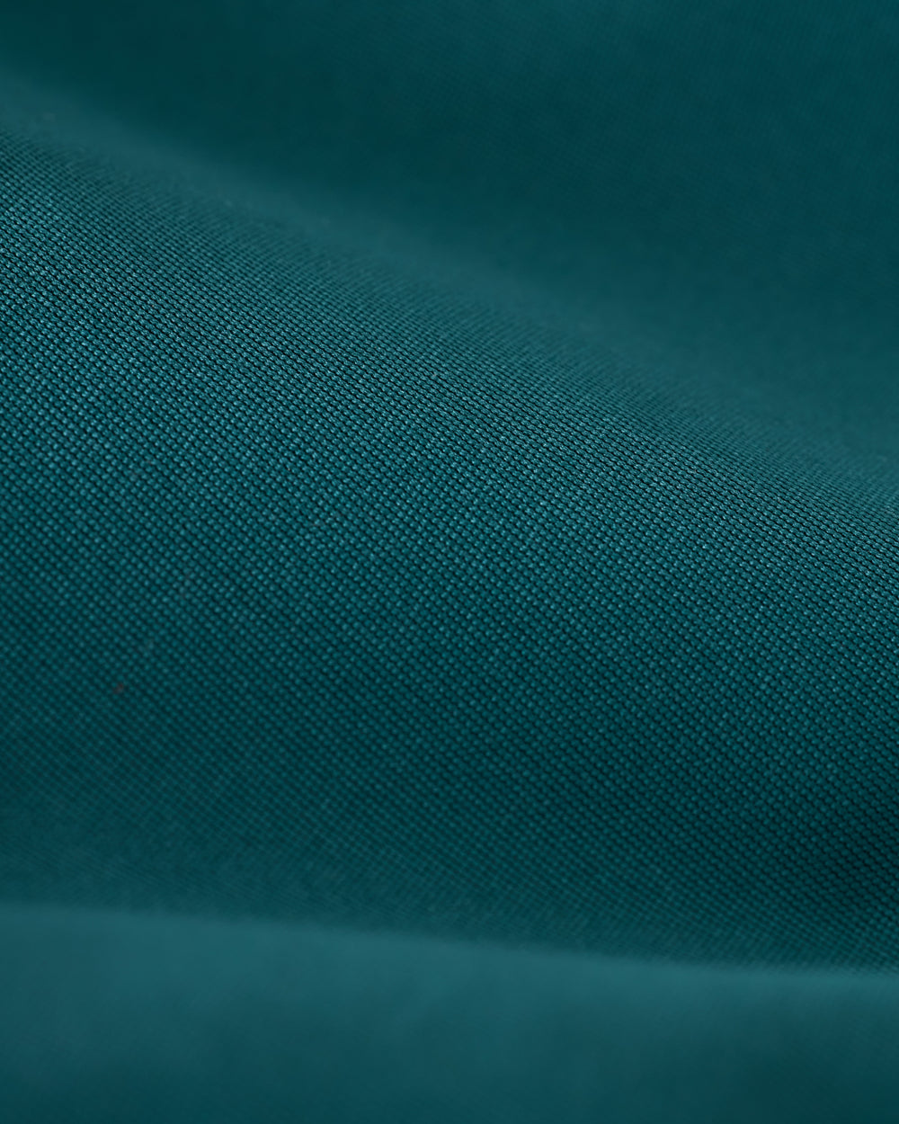 Close-up of a teal fabric with fine texture and visible weave pattern, akin to the high-quality construction of Dandy Del Mar’s Mallorca Swim-Walk Short in Tempest Blue.