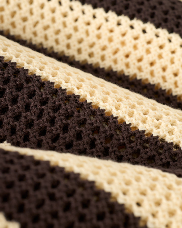 Close-up of a knitted fabric with alternating dark brown and cream stripes, reminiscent of the crochet design seen in Dandy Del Mar's Malta Crochet Dress - Tierra.