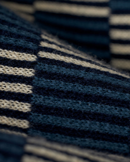 Close-up of The Martinique Sweater-Knit Shirt by Dandy Del Mar, featuring its anchor design with horizontal stripes in alternating navy blue and cream colors, and showcasing the detailed texture of the yarn.