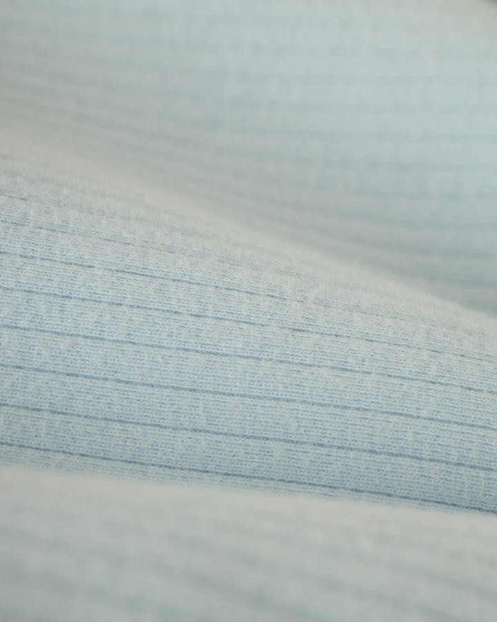 A detailed view of the Comet Grey Milan Rib Tank by Dandy Del Mar shows its light blue, textured ribbed fabric, reminiscent of a soft cotton blend.