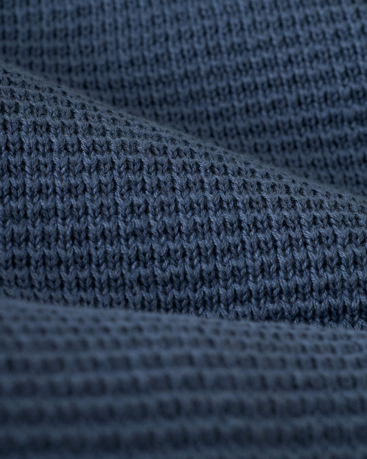 Close-up of the textured dark gray knit fabric from The Montego Knit Vest - Moontide by Dandy Del Mar, showcasing its visible stitching patterns.