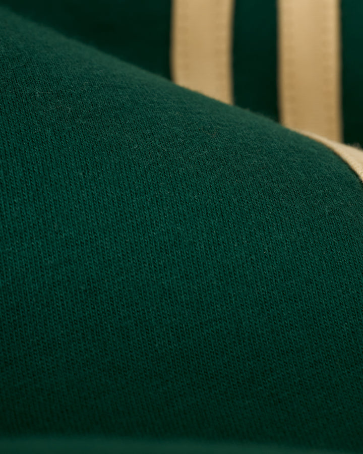 Close-up of The Nassau Tee - Albero by Dandy Del Mar, featuring green fabric with a beige stripe.