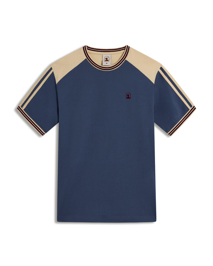 The Nassau Tee - Moontide by Dandy Del Mar is a blue and beige short-sleeve cotton jersey shirt with striped sleeves and collar, featuring an elegant small embroidered logo on the chest.