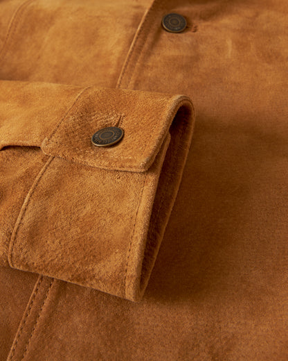 Close-up view of a sleeve from The San Juan Suede Leather Jacket - Sable by Dandy Del Mar, highlighting the rich sable suede leather with a buttoned cuff and jacquard lining.