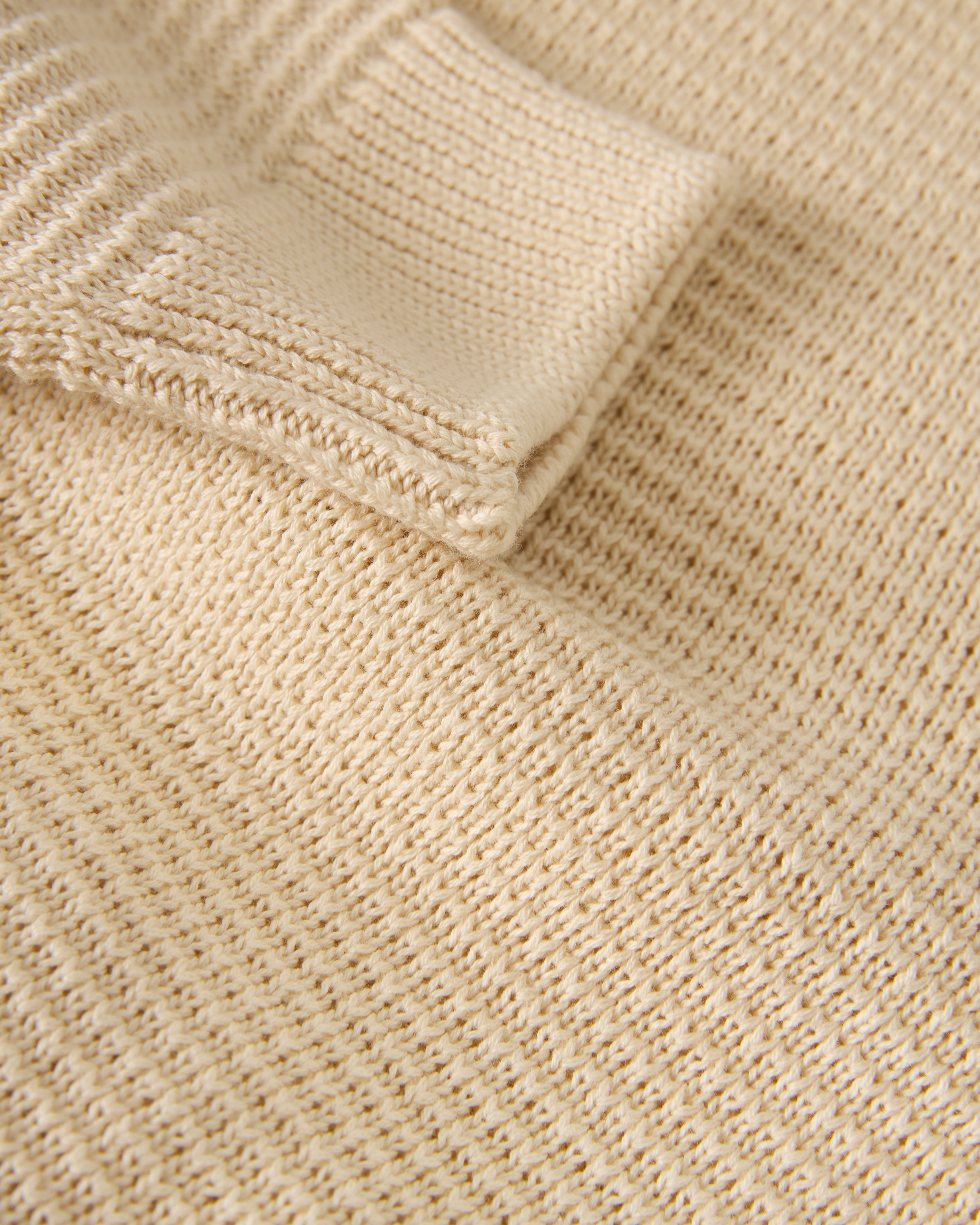 Close-up of The Sebastian Long Sleeve Polo in Vintage Ivory by Dandy Del Mar, highlighting its sweater-knit cotton texture and folded edge.