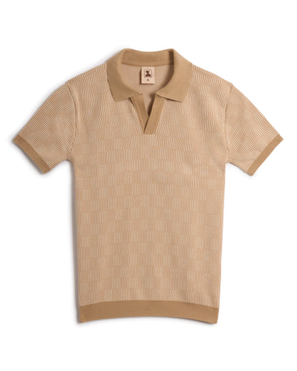 Introducing The Sebastian Knit Polo - Shell by Dandy Del Mar: a beige short-sleeve, buttonless polo with an elegant texture, refined collar, and subtle logo tag. Experience Italian knitwear luxury in every stitch.