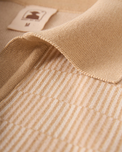 A close-up of The Sebastian Knit Polo - Shell from Dandy Del Mar reveals the elegance of Italian knit craftsmanship, featuring a textured ribbed pattern and folded collar with a visible 'M' size tag.