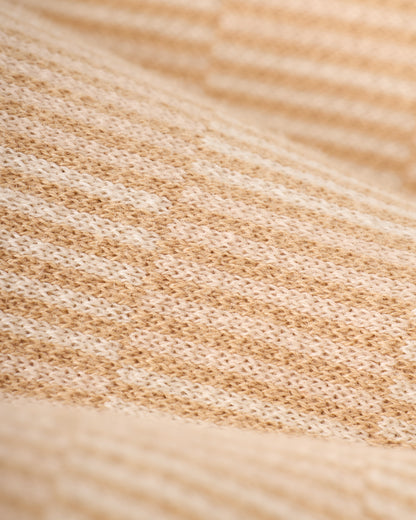 Close-up of The Sebastian Knit Polo - Shell by Dandy Del Mar, showcasing a beige Italian knit fabric with textured pattern and alternating light and dark stripes.