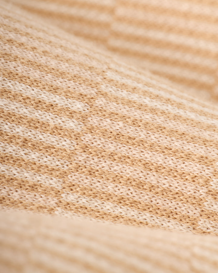 Close-up image of the beige and white textured fabric with a woven pattern, displaying a grid-like design, from The Sebastian Knit Polo Shirt - Shell by Dandy Del Mar.