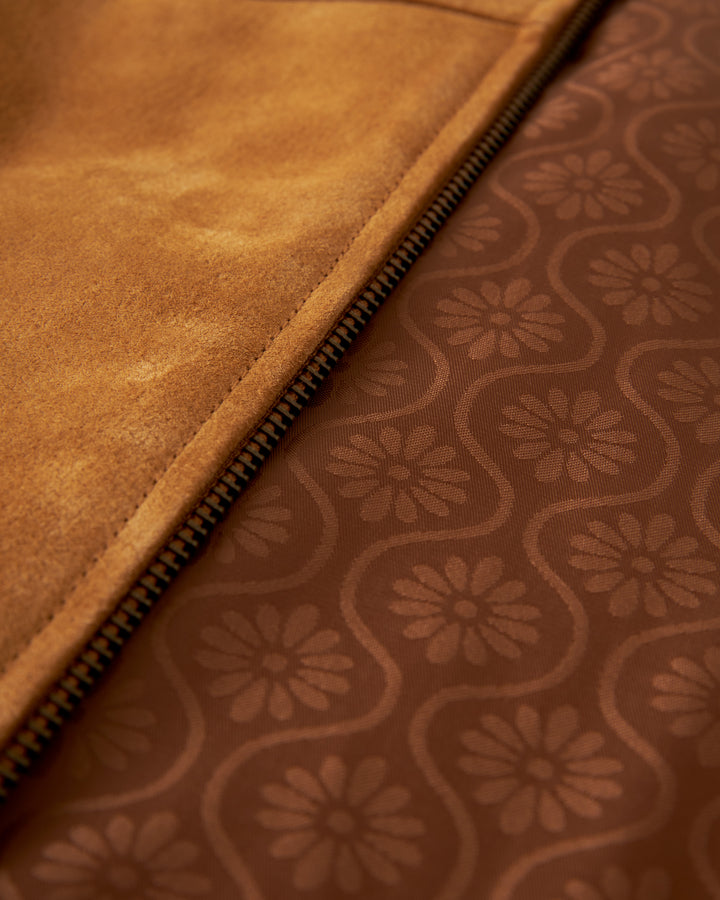 Close-up of the interior of The Sicily Leather Jacket - Sable by Dandy Del Mar, showcasing a jacquard lining with intricate floral designs and a visible zip.