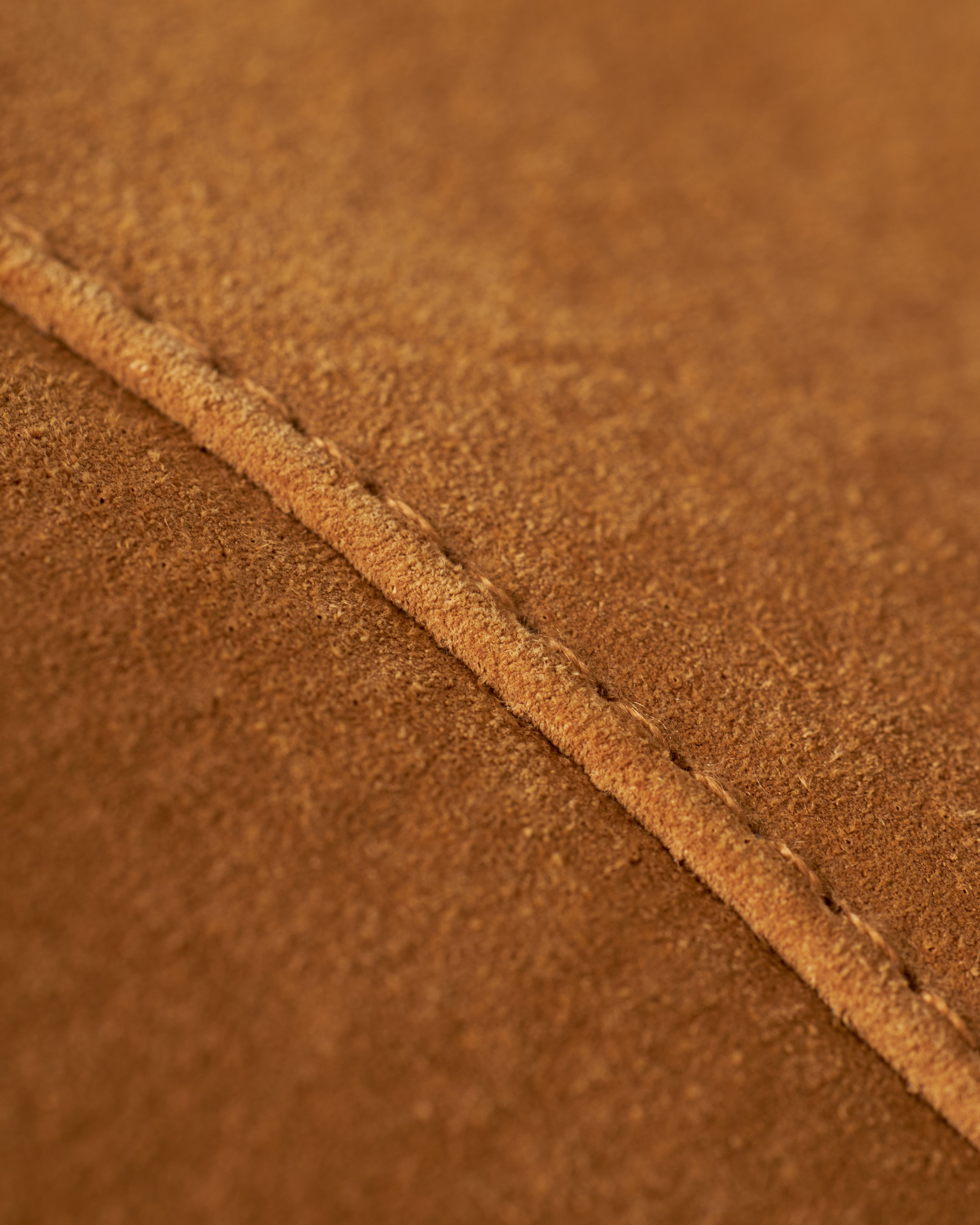 Close-up image of The Sicily Leather Jacket - Sable by Dandy Del Mar, showcasing a detailed view of the brown suede leather surface with visible seam stitching.