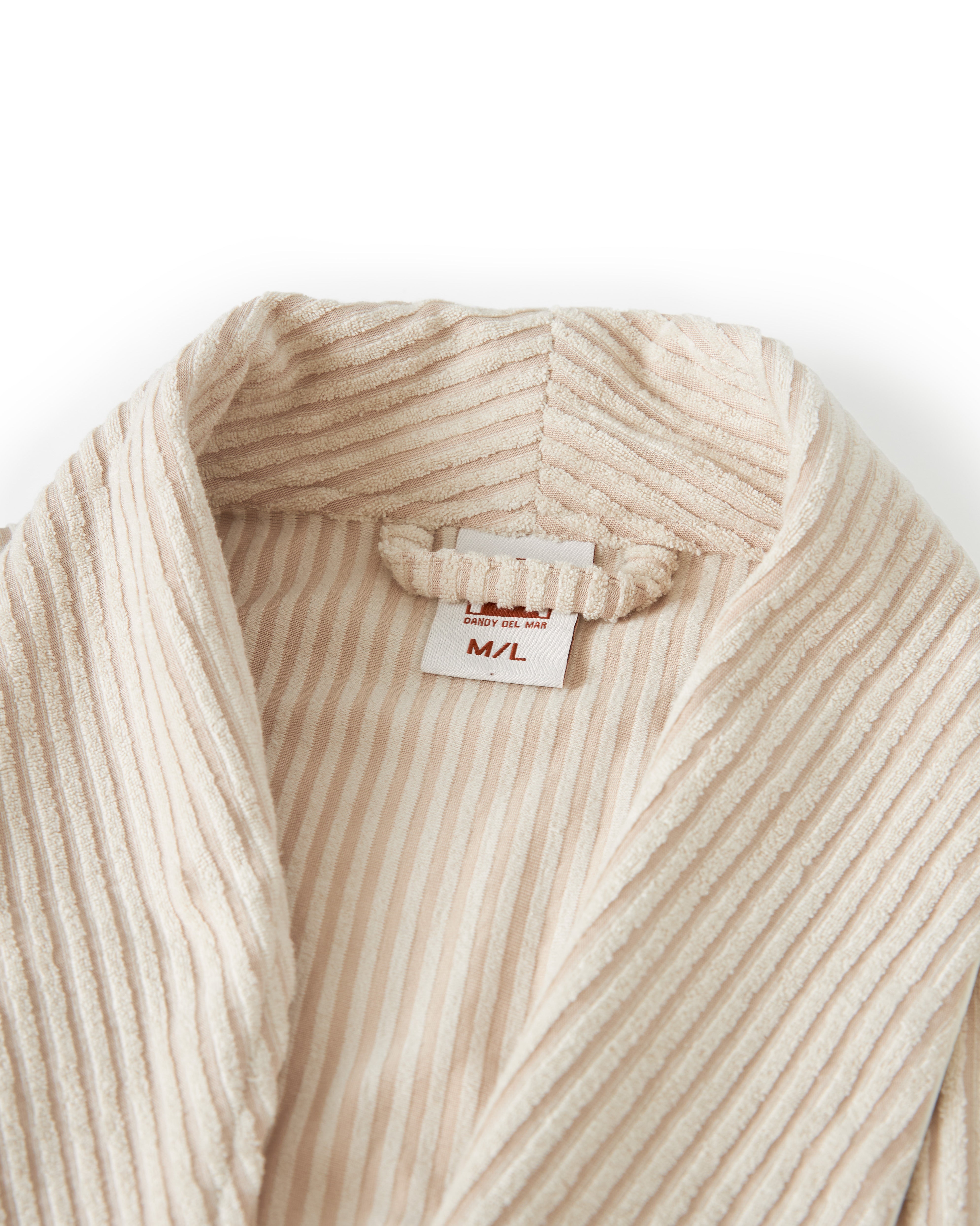 Close-up of The Tropez Jacquard Robe - Scallop Stripe by Dandy Del Mar, showcasing its cream-colored, ribbed bathrobe collar with a visible size tag indicating M/L. The jacquard striped terry cloth adds an elegant touch to the luxurious fabric.