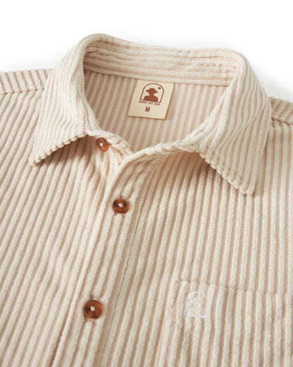 Close-up of The Tropez Jacquard Shirt - Scallop Stripe from Dandy Del Mar, featuring brown buttons, a chest pocket with an embroidered logo, and a size tag marked "M.