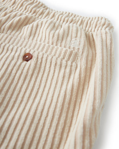 Close-up of The Tropez Jacquard Short - Scallop Stripe by Dandy Del Mar, showcasing its beige corduroy texture, elastic waistband, and a small pocket adorned with a brown button.