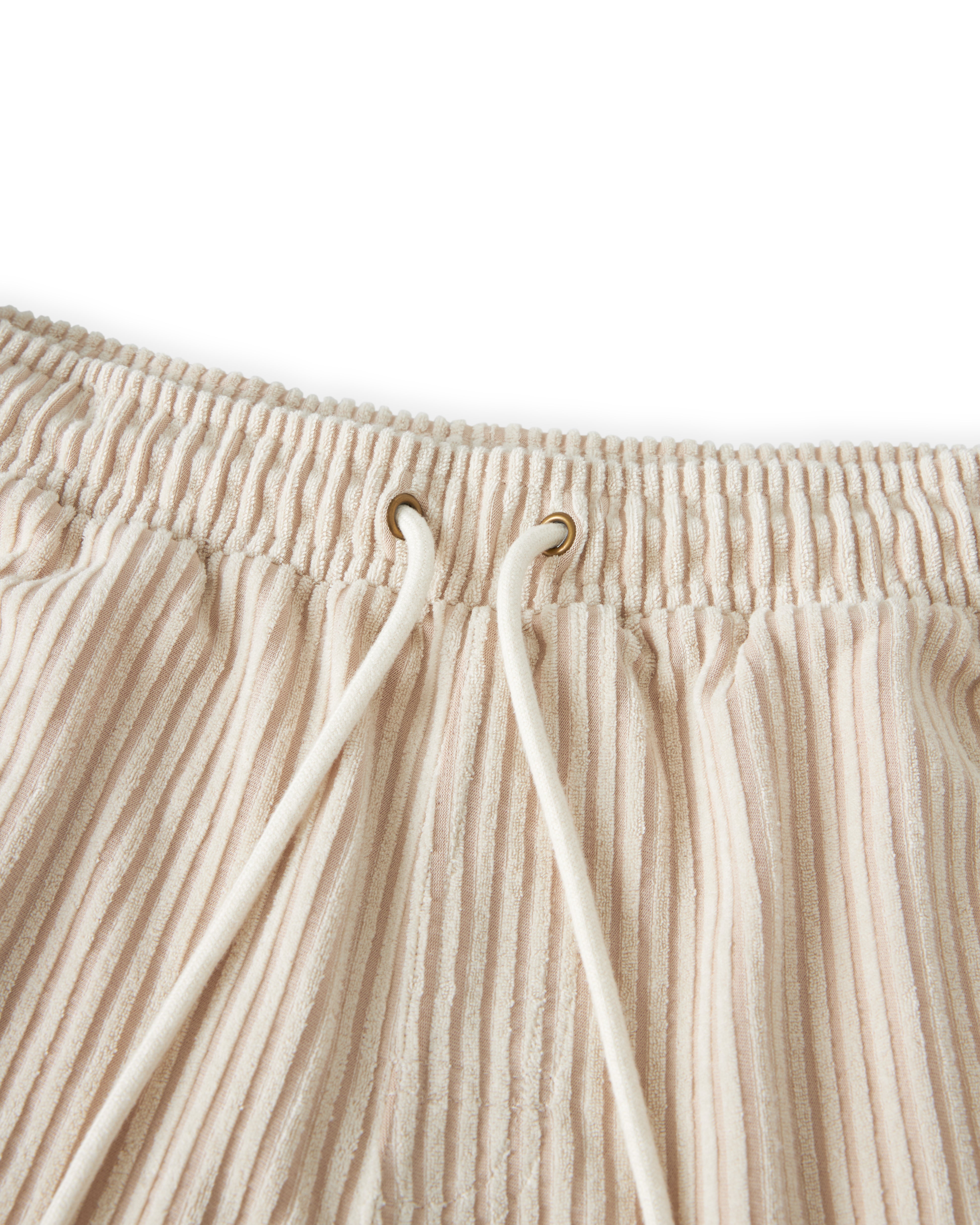 Close-up of beige pleated pants with white drawstrings and an elastic waistband, set against a white background, reminiscent of Côte d'Azur shorts by Dandy Del Mar's The Tropez Jacquard Short - Scallop Stripe.